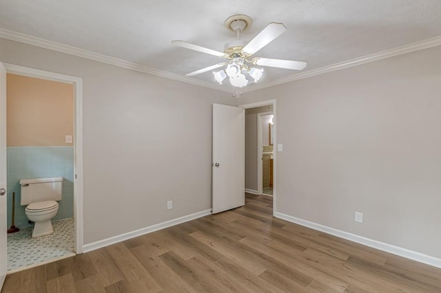unfurnished bedroom featuring ceiling fan, ensuite bathroom, light hardwood / wood-style flooring, and ornamental molding