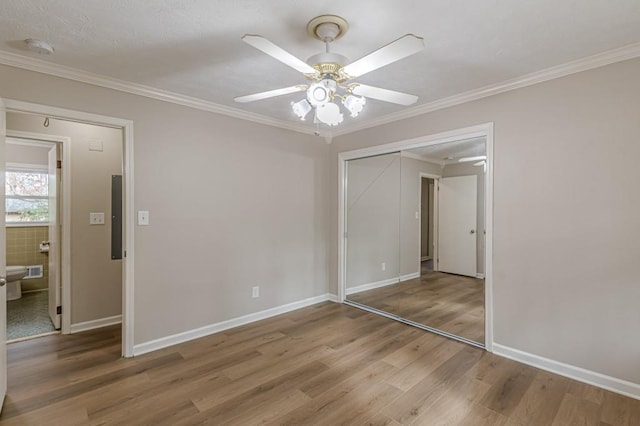 unfurnished bedroom with crown molding, ceiling fan, hardwood / wood-style floors, and a closet