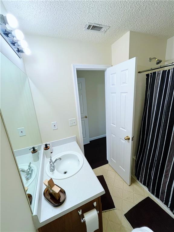 7104 Georges Way, Morrow, GA 30260 - bathroom with vanity, tile patterned floors, curtained shower, and a textured ceiling