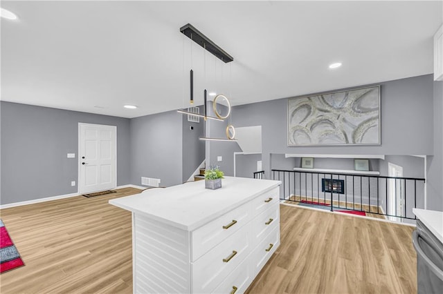 kitchen featuring white cabinetry, a kitchen island, light wood-type flooring, and decorative light fixtures