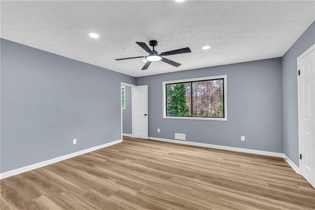 spare room with ceiling fan, a textured ceiling, and light wood-type flooring