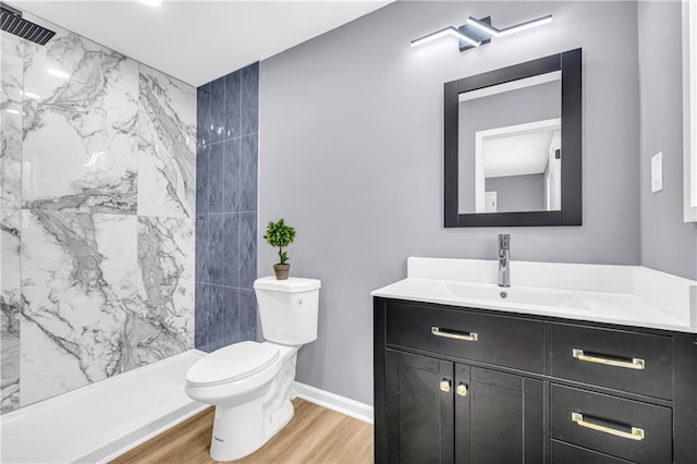 bathroom featuring hardwood / wood-style flooring, vanity, tiled shower, and toilet