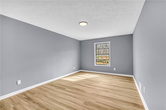 spare room with a textured ceiling and light hardwood / wood-style flooring