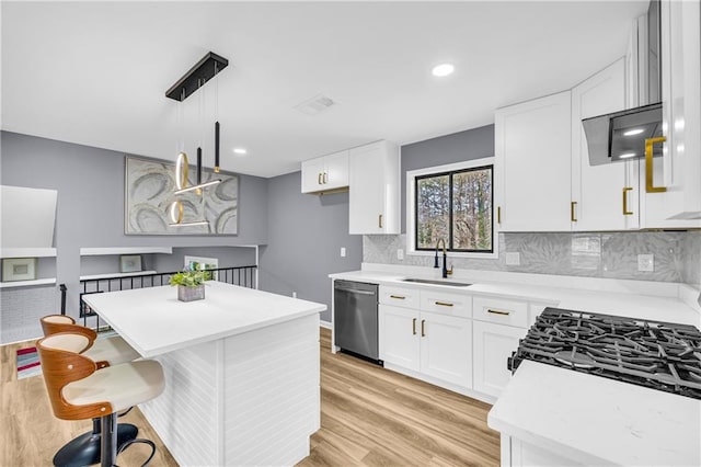 kitchen featuring sink, stainless steel dishwasher, white cabinets, and decorative light fixtures