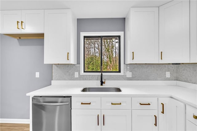 kitchen with sink, dishwasher, white cabinetry, backsplash, and light hardwood / wood-style floors