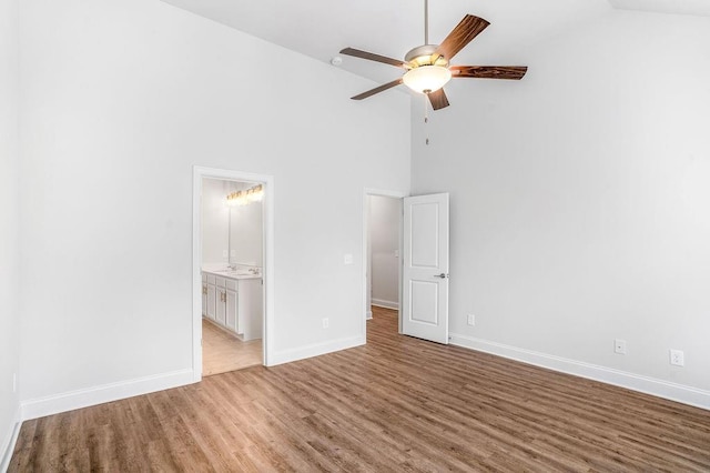 unfurnished bedroom featuring baseboards, high vaulted ceiling, and wood finished floors