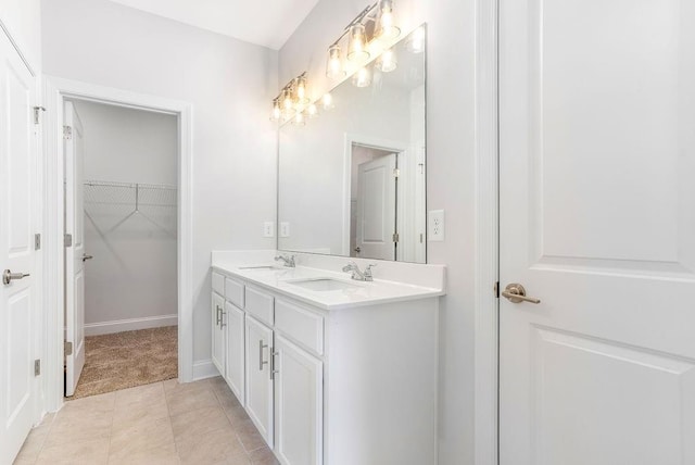 full bathroom with double vanity, baseboards, a spacious closet, and a sink