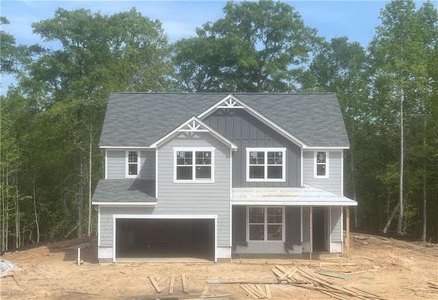 view of front of home featuring driveway, an attached garage, a shingled roof, and board and batten siding