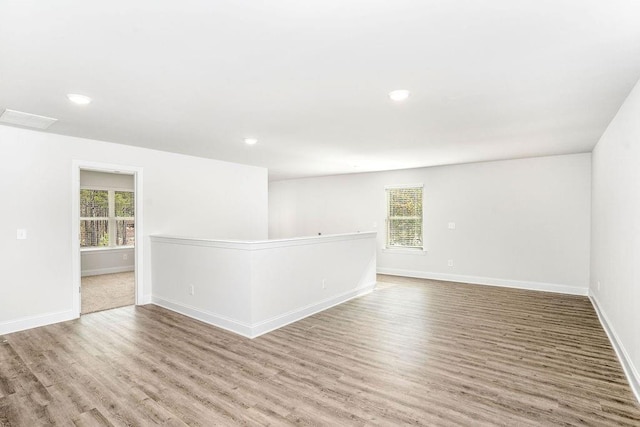 spare room featuring baseboards, a healthy amount of sunlight, and wood finished floors