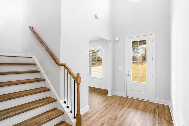 entryway with visible vents, light wood-style flooring, baseboards, and stairway