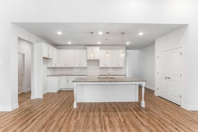 kitchen with light wood-type flooring, decorative backsplash, and baseboards
