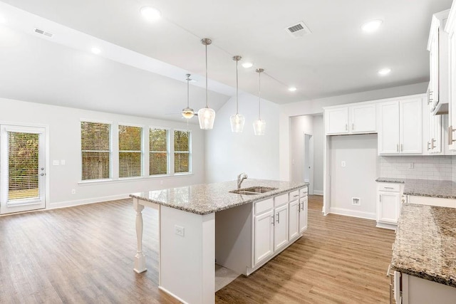 kitchen with a sink, light wood finished floors, baseboards, and visible vents