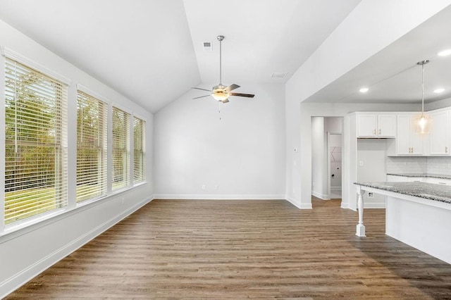 unfurnished living room with a wealth of natural light, vaulted ceiling, a ceiling fan, and light wood-style floors