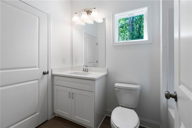 bathroom featuring vanity, toilet, wood finished floors, and baseboards