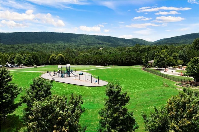 view of home's community with playground community, a yard, a forest view, and a mountain view