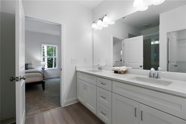 full bathroom featuring double vanity, a shower with shower door, wood finished floors, and a sink