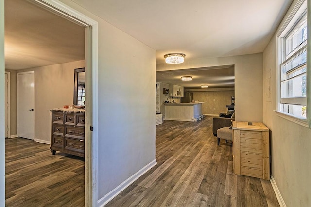 corridor featuring dark wood finished floors and baseboards