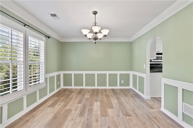 spare room with visible vents, light wood-style floors, crown molding, and a notable chandelier