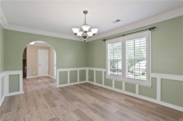 spare room with visible vents, crown molding, an inviting chandelier, light wood-style floors, and arched walkways