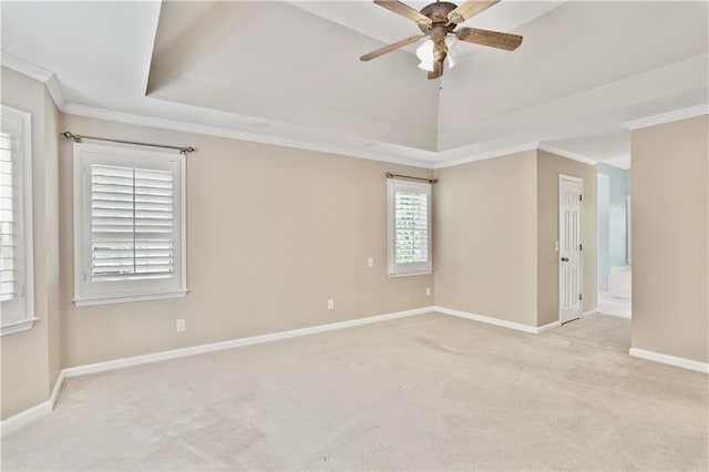 spare room with crown molding, carpet flooring, baseboards, a tray ceiling, and a ceiling fan