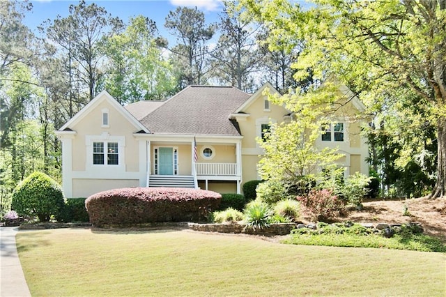 view of front of house with a shingled roof, a front lawn, and stucco siding