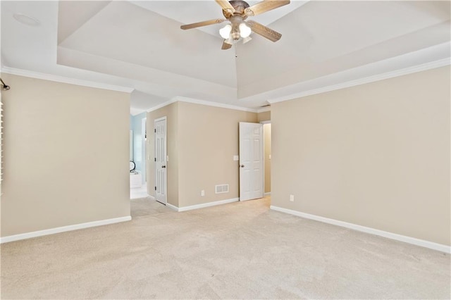spare room with ceiling fan, light carpet, a tray ceiling, and visible vents