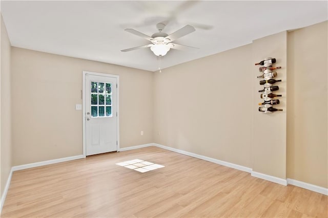 spare room with baseboards, ceiling fan, and light wood-style flooring