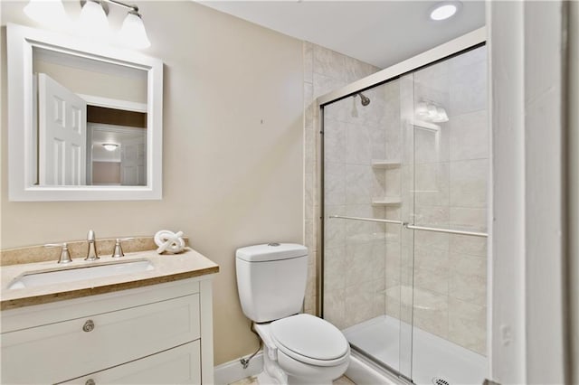 bathroom featuring vanity, baseboards, toilet, and a shower stall