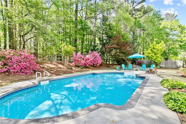 outdoor pool featuring fence and a patio area