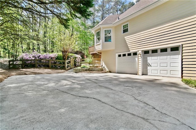 view of side of property featuring concrete driveway, fence, and a garage