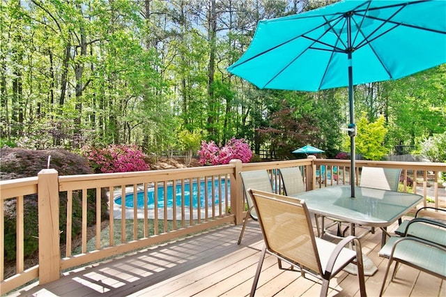 wooden deck featuring outdoor dining area and an outdoor pool