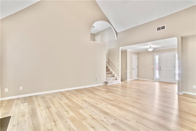 unfurnished living room with baseboards, a high ceiling, light wood finished floors, and stairs