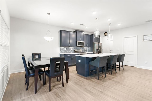 138 Daffodil Lndg, Dallas, GA 30132 - kitchen featuring stainless steel appliances, decorative backsplash, a center island with sink, light wood-style flooring, and light countertops