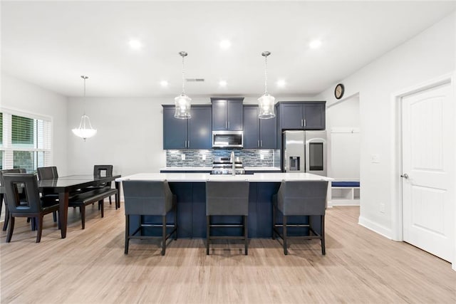138 Daffodil Lndg, Dallas, GA 30132 - kitchen featuring appliances with stainless steel finishes, light countertops, an island with sink, tasteful backsplash, and light wood-style floors