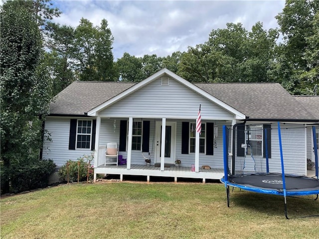 single story home featuring a trampoline, covered porch, and a front yard