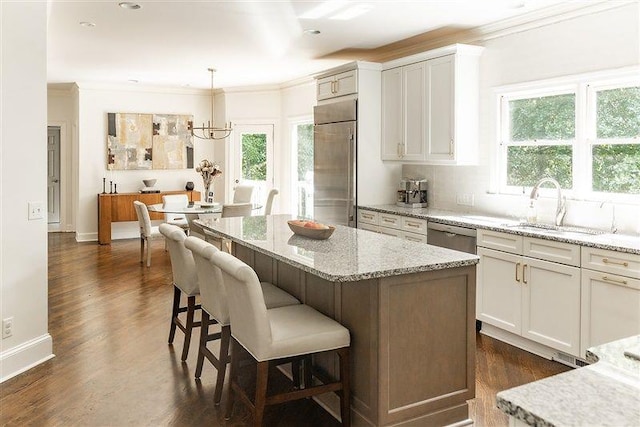 kitchen with white cabinetry, stainless steel appliances, decorative light fixtures, and sink