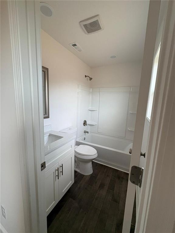 full bathroom with wood-type flooring, toilet, shower / bath combination, and vanity