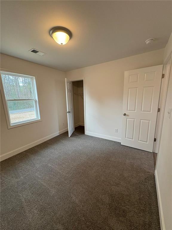 unfurnished bedroom featuring a closet and dark colored carpet