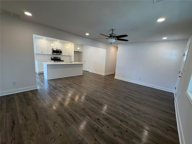 unfurnished living room featuring sink, dark wood-type flooring, and ceiling fan