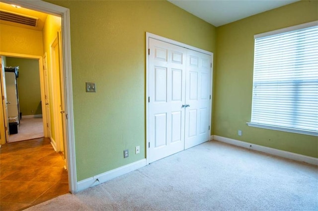 unfurnished bedroom featuring light carpet and a closet