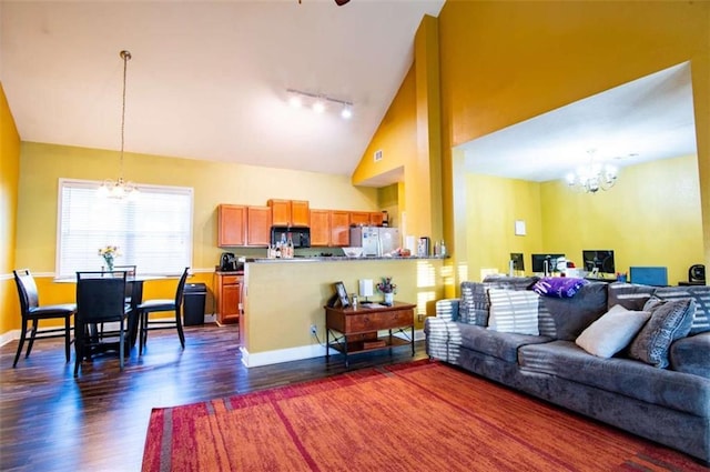 living room with high vaulted ceiling, dark wood-type flooring, track lighting, and a notable chandelier