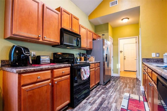 kitchen featuring hardwood / wood-style floors, vaulted ceiling, and black appliances