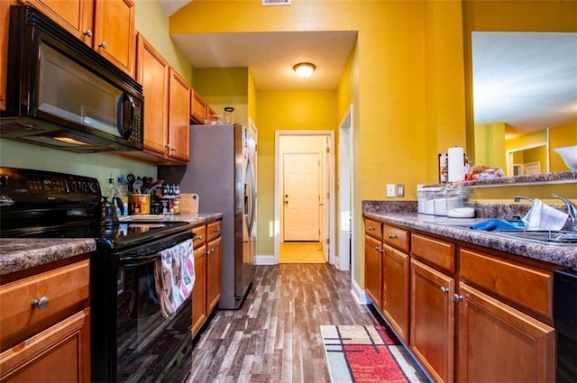 kitchen with sink, dark hardwood / wood-style floors, and black appliances