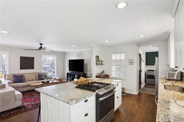 kitchen with dark wood-type flooring, a kitchen bar, light stone counters, stainless steel range with gas stovetop, and white cabinets