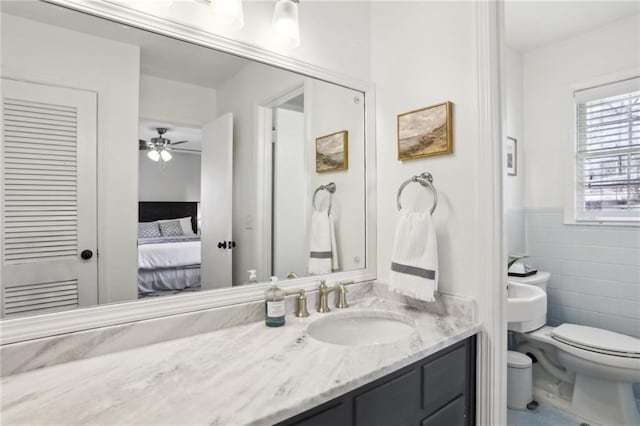 bathroom with vanity, tile walls, ceiling fan, and toilet