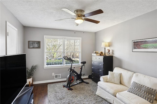 workout room featuring ceiling fan, a textured ceiling, and dark hardwood / wood-style flooring