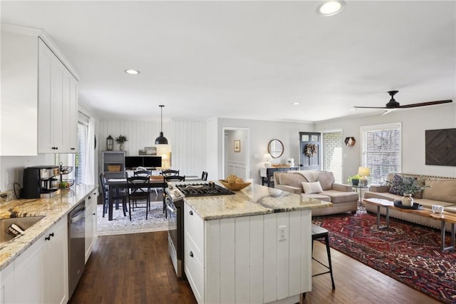 kitchen featuring white cabinets, hanging light fixtures, a center island, stainless steel appliances, and dark wood-type flooring