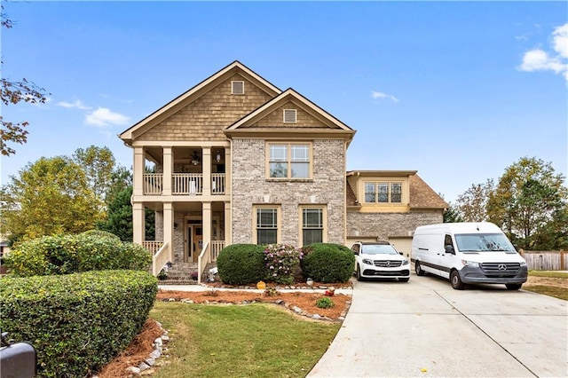 view of front facade featuring a garage, ceiling fan, a balcony, a front yard, and concrete driveway