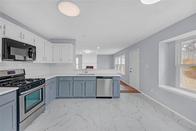 kitchen with sink, white cabinetry, stainless steel appliances, tasteful backsplash, and kitchen peninsula