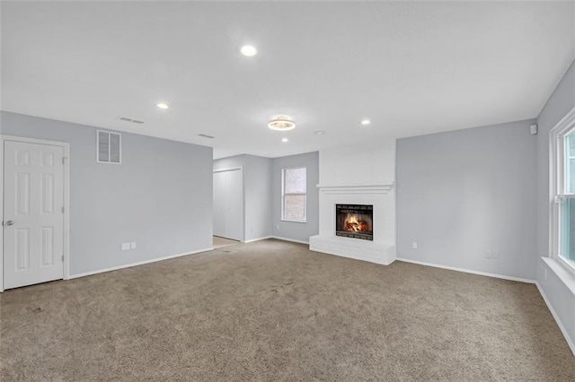 unfurnished living room featuring light carpet and a fireplace